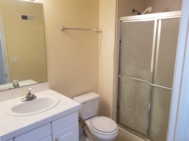 bathroom with vanity, a shower with shower door, and toilet