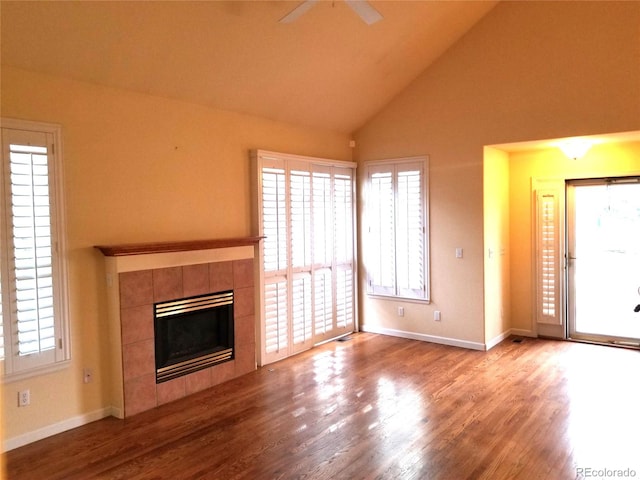 unfurnished living room featuring light wood-type flooring, high vaulted ceiling, ceiling fan, and a tiled fireplace