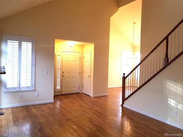 entryway with hardwood / wood-style floors and high vaulted ceiling