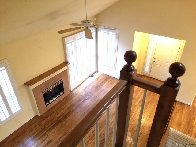 living room featuring hardwood / wood-style flooring, ceiling fan, lofted ceiling, and a tiled fireplace