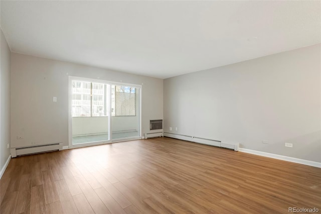 unfurnished room with light wood-type flooring and a baseboard heating unit