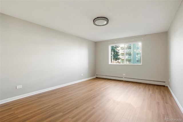 unfurnished room featuring a baseboard radiator and light hardwood / wood-style floors