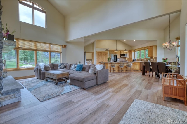 living room featuring an inviting chandelier, a high ceiling, and light hardwood / wood-style flooring