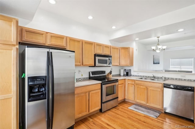 kitchen with sink, hanging light fixtures, stainless steel appliances, light hardwood / wood-style flooring, and a chandelier