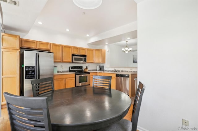 kitchen featuring light hardwood / wood-style flooring, stainless steel appliances, sink, decorative light fixtures, and an inviting chandelier