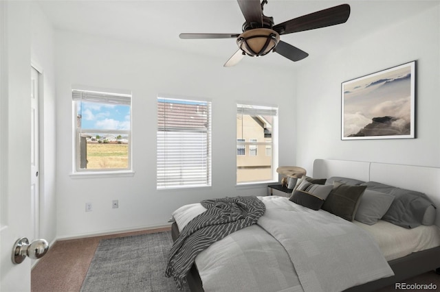 carpeted bedroom with multiple windows and ceiling fan