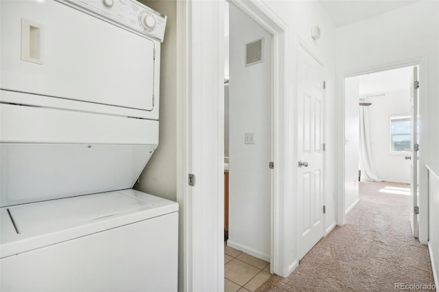 laundry area featuring stacked washer and dryer and light colored carpet