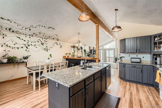 kitchen featuring a sink, a textured ceiling, and vaulted ceiling with beams
