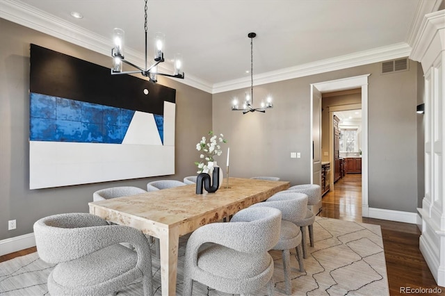 dining area with baseboards, visible vents, wood finished floors, crown molding, and a chandelier