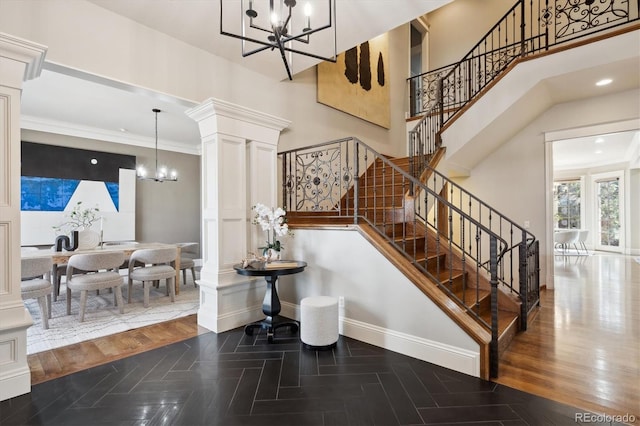 staircase with ornate columns, baseboards, wood finished floors, and an inviting chandelier