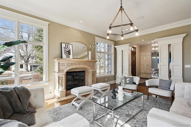 living room with a healthy amount of sunlight, decorative columns, wood finished floors, and a high end fireplace