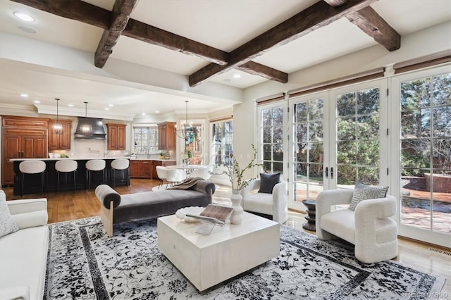 living area featuring recessed lighting, light wood-type flooring, beam ceiling, and a notable chandelier