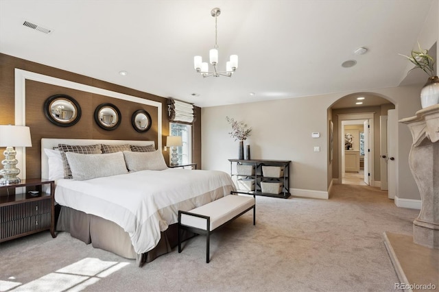 bedroom with baseboards, visible vents, arched walkways, light colored carpet, and a chandelier