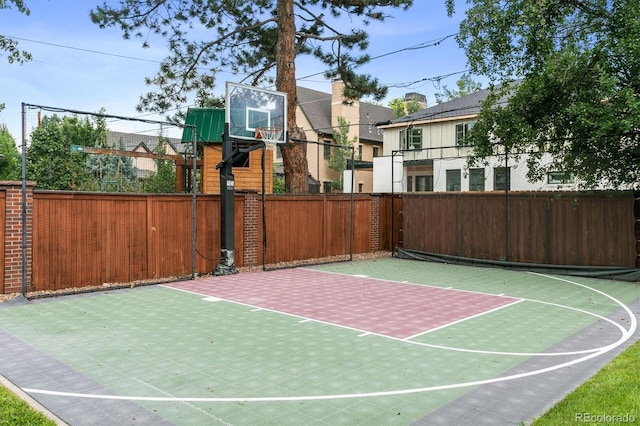 view of basketball court with fence and basketball hoop