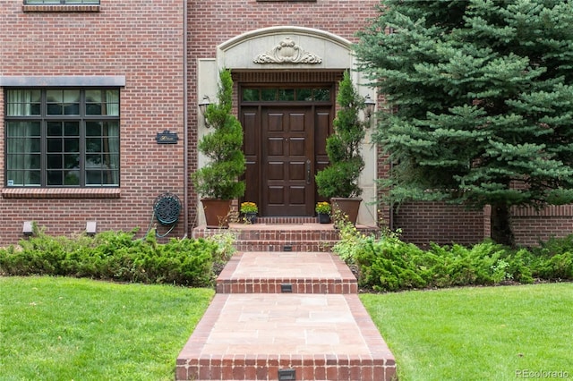 doorway to property with a yard and brick siding