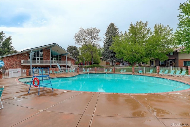 community pool with a patio and fence