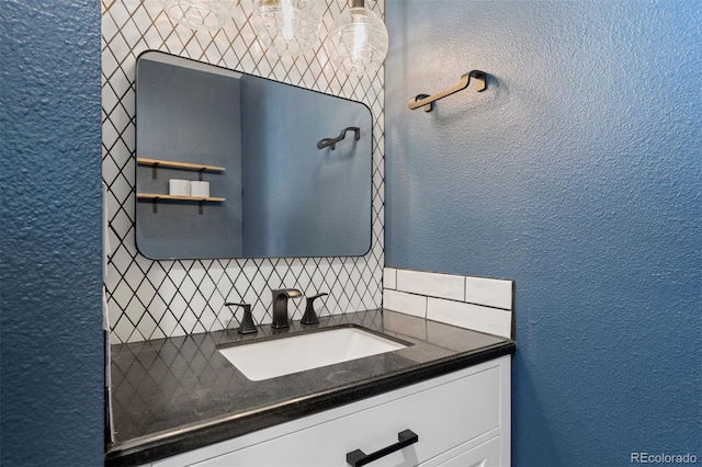 bathroom featuring vanity, backsplash, and a textured wall