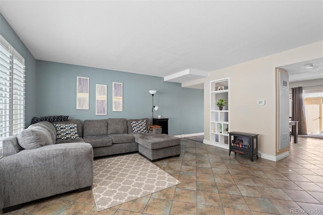 living area with built in features, a wood stove, visible vents, and baseboards