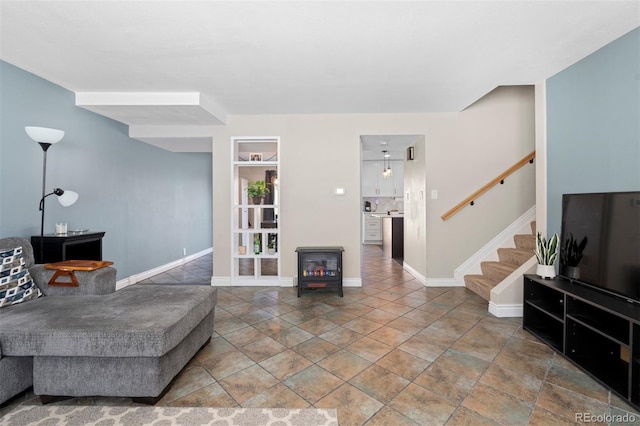 living room with a wood stove, baseboards, and stairway