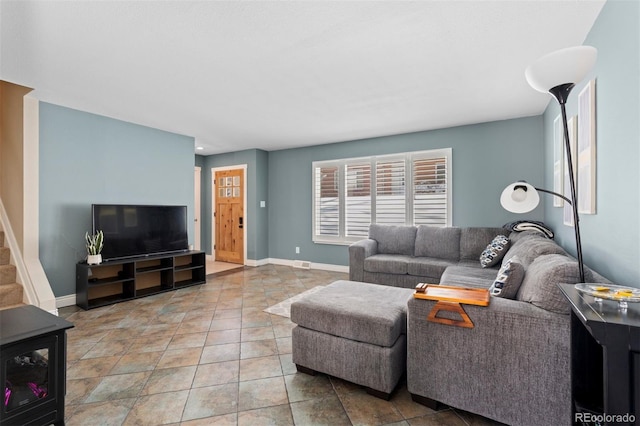 living area featuring stairway, light tile patterned flooring, and baseboards