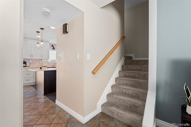 stairway with baseboards and tile patterned floors