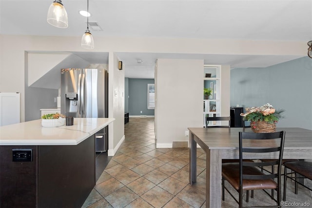 kitchen featuring a kitchen island, visible vents, baseboards, light countertops, and tile patterned floors