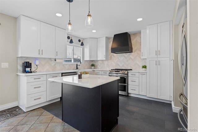 kitchen featuring stainless steel appliances, wall chimney range hood, light countertops, and white cabinets