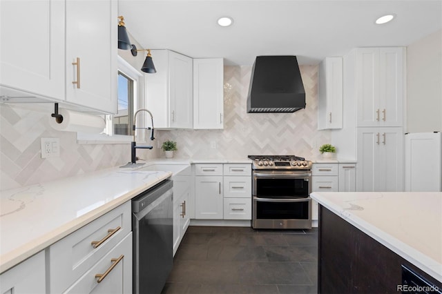 kitchen featuring stainless steel appliances, white cabinets, a sink, light stone countertops, and wall chimney exhaust hood