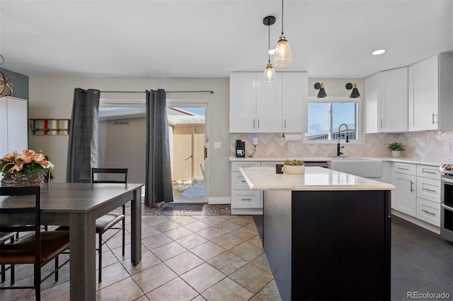 kitchen featuring backsplash, light countertops, a sink, and a center island