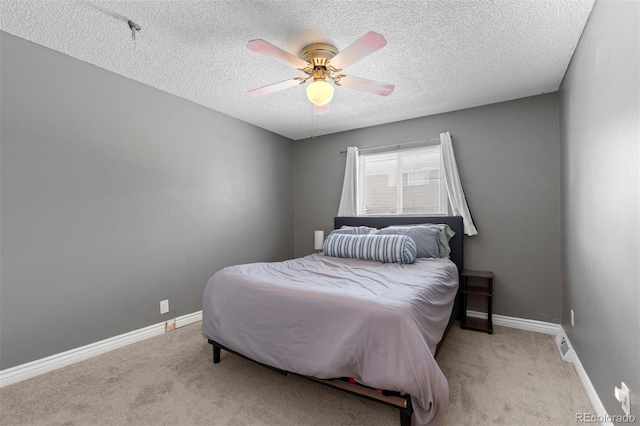 carpeted bedroom with a textured ceiling, a ceiling fan, and baseboards