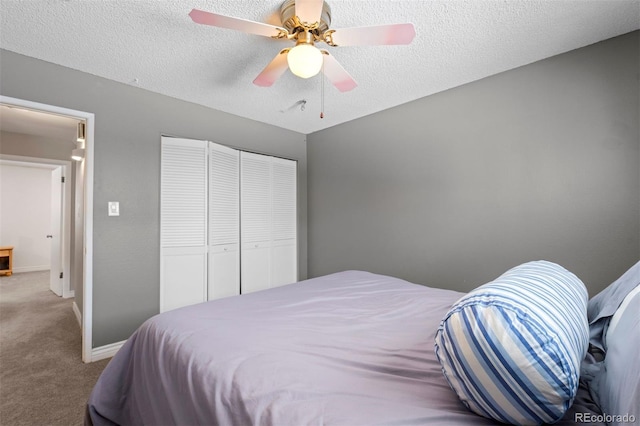 bedroom with a textured ceiling, ceiling fan, carpet flooring, baseboards, and a closet