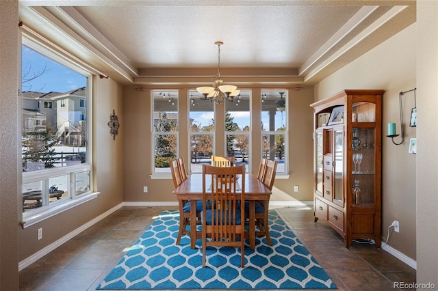 dining room with dark tile patterned flooring, an inviting chandelier, and a tray ceiling