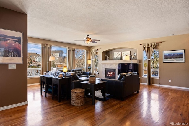 living room featuring ceiling fan, dark hardwood / wood-style floors, and a textured ceiling