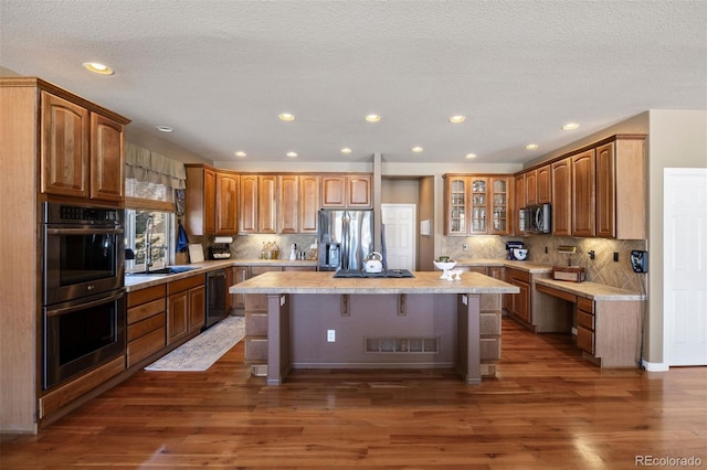 kitchen featuring a center island, a breakfast bar area, dark wood-type flooring, and black appliances