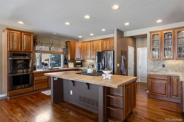 kitchen featuring a center island, a textured ceiling, appliances with stainless steel finishes, dark hardwood / wood-style flooring, and decorative backsplash