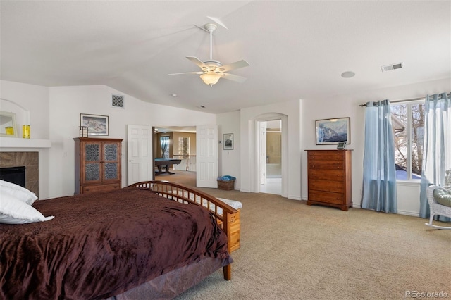 carpeted bedroom with a tile fireplace, lofted ceiling, and ensuite bathroom