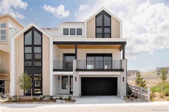 contemporary home with a garage, driveway, fence, and a balcony