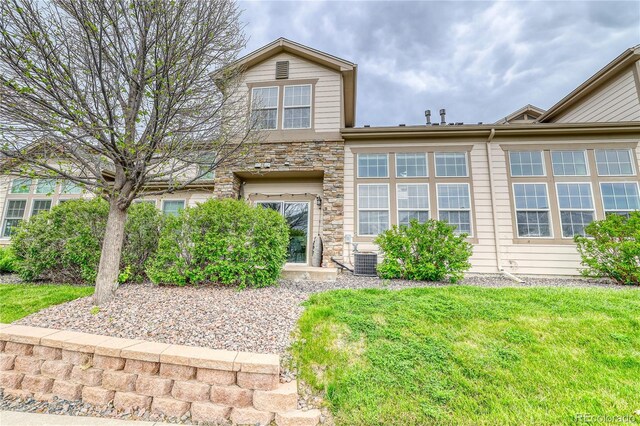 23070 York Ave, Parker, CO 80138 - view of front of property with stone siding, central air condition unit, and a front lawn
