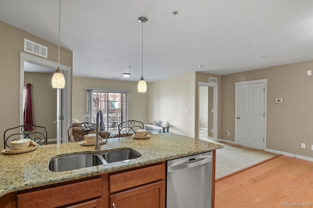 kitchen with hanging light fixtures, light stone countertops, sink, and stainless steel dishwasher