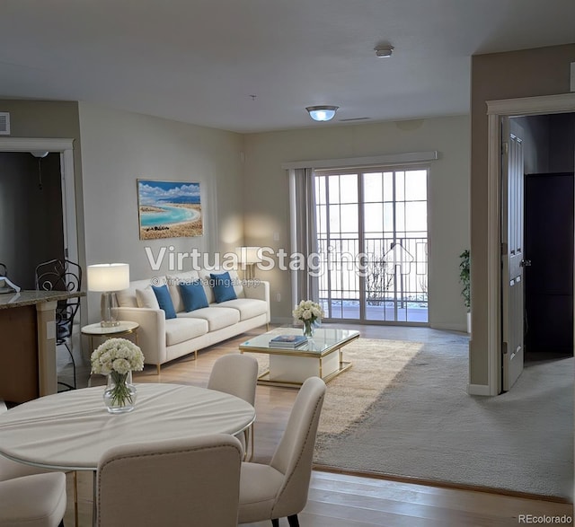 living area with light wood-type flooring, visible vents, and baseboards