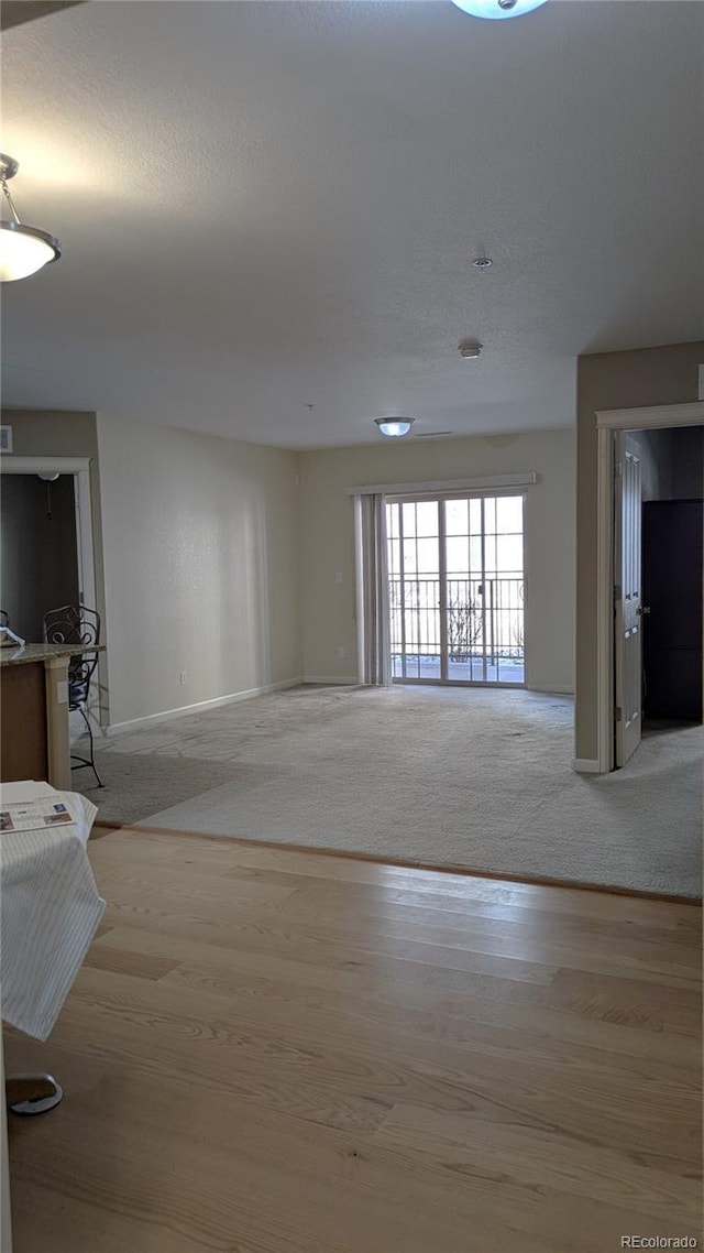 unfurnished room featuring light wood-type flooring, baseboards, and a textured ceiling