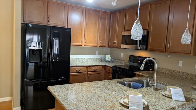 kitchen with black appliances, brown cabinetry, light stone countertops, and a sink