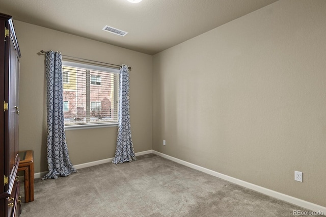 empty room with baseboards, visible vents, and carpet floors