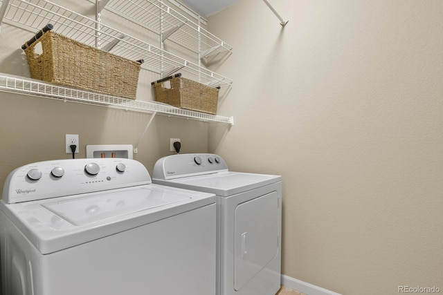 washroom with laundry area, washing machine and dryer, and baseboards