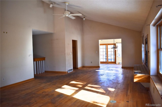 unfurnished living room featuring high vaulted ceiling, dark hardwood / wood-style floors, ceiling fan, and french doors