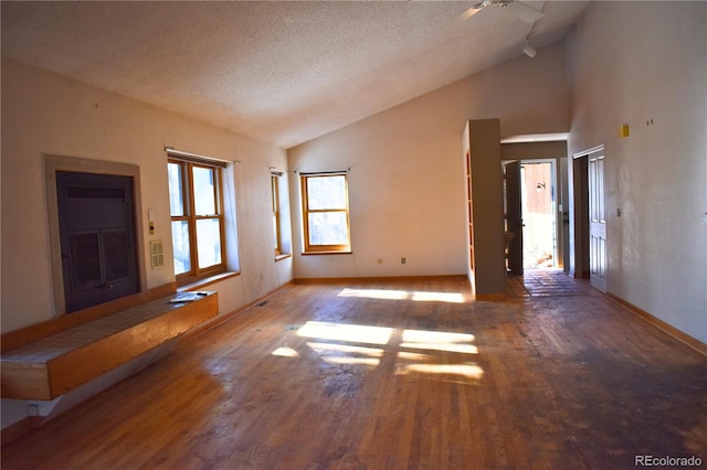 spare room featuring hardwood / wood-style flooring, high vaulted ceiling, and a textured ceiling