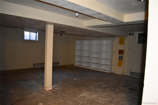 basement featuring a baseboard heating unit and a textured ceiling