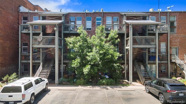 view of building exterior featuring stairs and uncovered parking