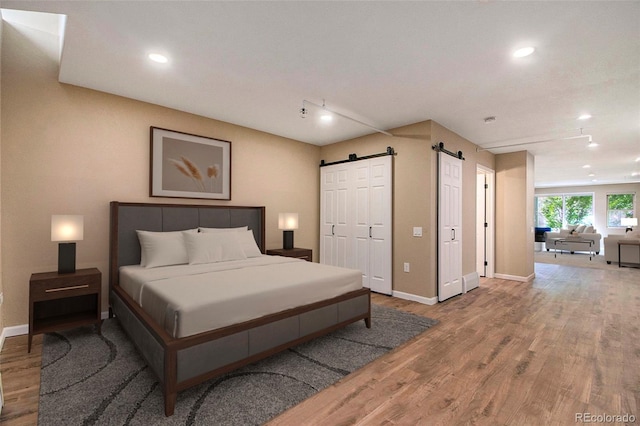 bedroom featuring wood-type flooring and a barn door