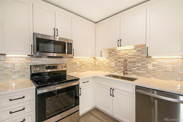 kitchen featuring sink, appliances with stainless steel finishes, white cabinetry, decorative backsplash, and light wood-type flooring